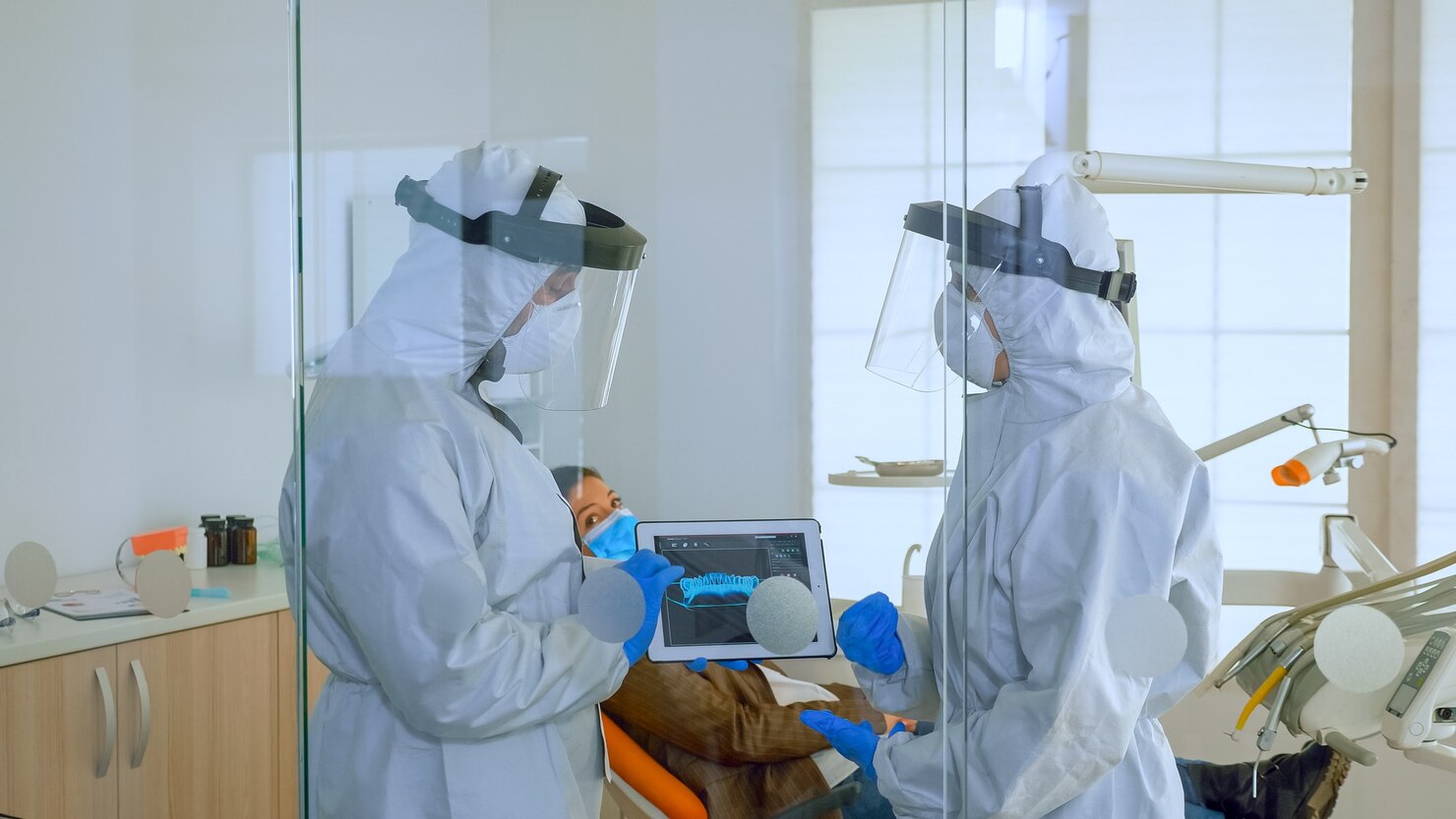 dentist-doctors-overall-using-tablet-explaining-dental-x-ray-stomatologic-office-coronavirus-man-wearing-face-shield-mask-showing-nusrse-radiography-using-digital-device_482257-3541